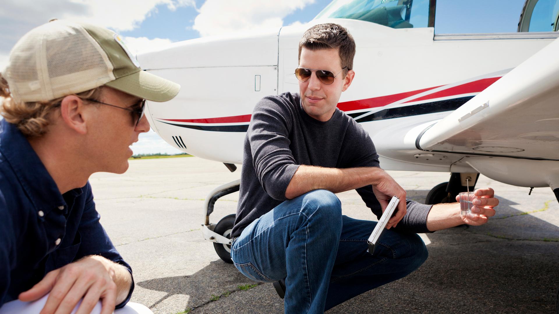 two men discussing airplane on tarmac