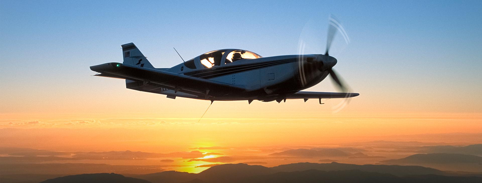 Plane silhouette in sky with sunset in background